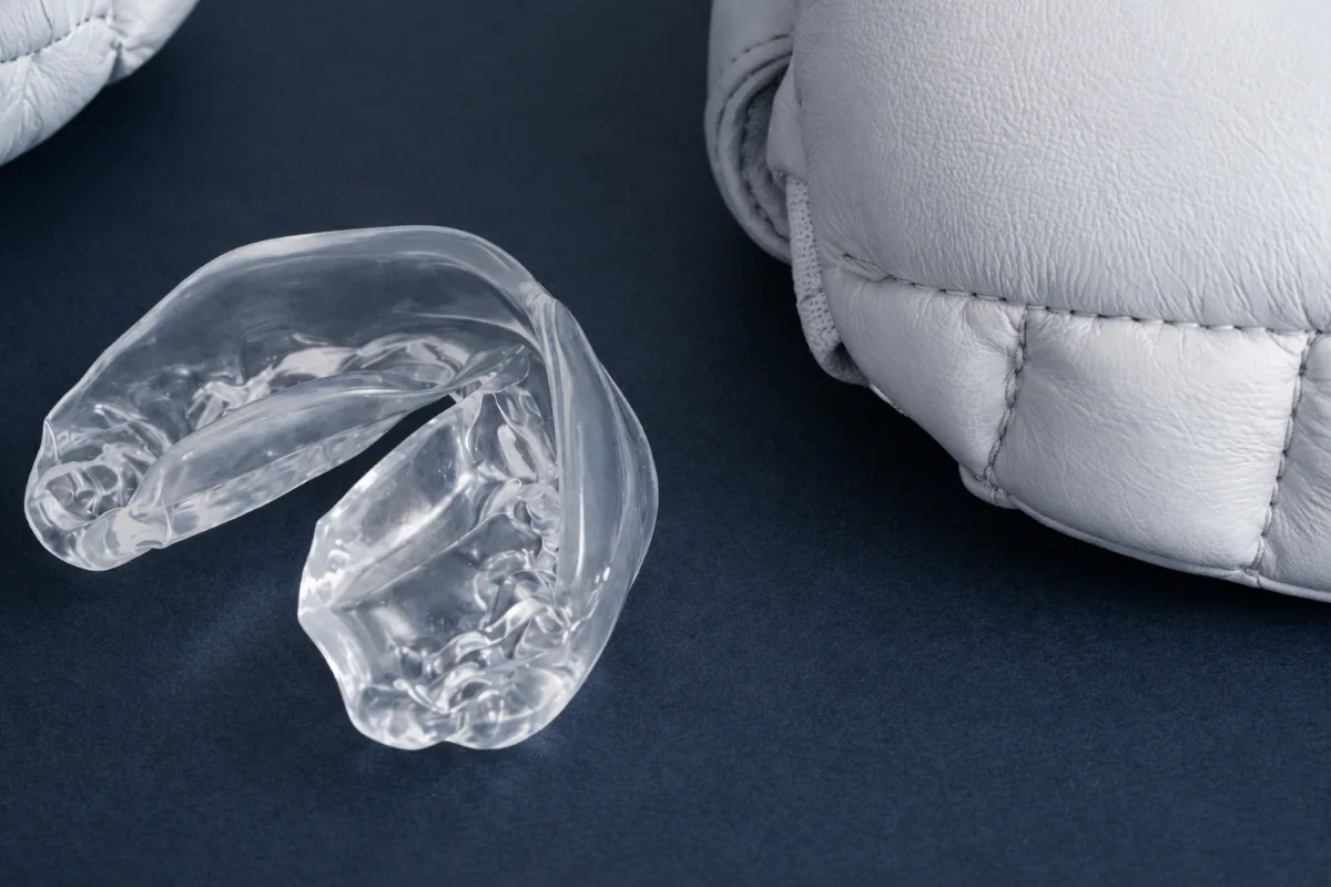 Custom Occlusal Night Guard in North York | Bruxism & Teeth Grinding Protection Clear custom occlusal night guard displayed beside boxing gloves in North York.