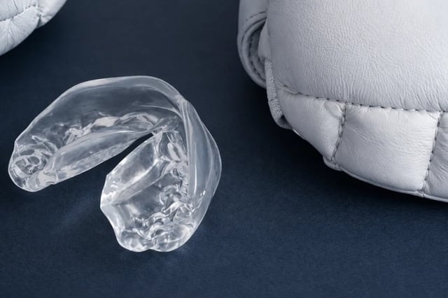 Custom Occlusal Night Guard in North York | Bruxism & Teeth Grinding Protection Clear custom occlusal night guard displayed beside boxing gloves in North York.